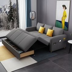 a living room with a gray couch, yellow pillows and a painting on the wall