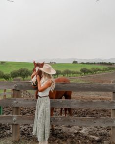 a woman standing next to a brown horse