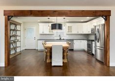 an open kitchen and dining room with white cabinets, stainless steel appliances and wood flooring