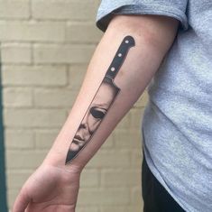 a person with a knife tattoo on their arm