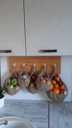 three baskets hanging on the wall with fruit in them