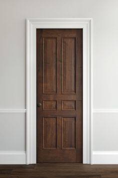 an empty room with a wooden door and hard wood flooring on the side wall