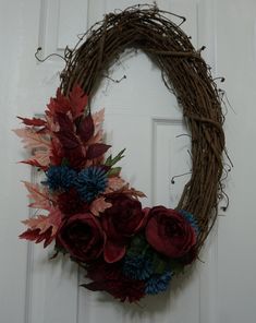 a wreath is hanging on the door with red and blue flowers in front of it