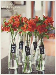 three clear vases with flowers in them on a counter top, one has a price tag and the other is empty