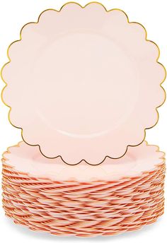 a stack of pink and gold plates with scalloped rims on top of each plate