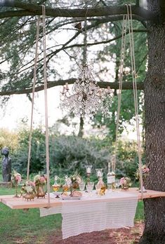 a table that has some food on it and is hanging from a tree in the grass