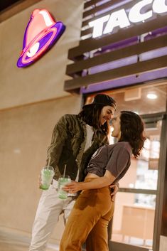 a man and woman kissing in front of a neon sign that reads, osat