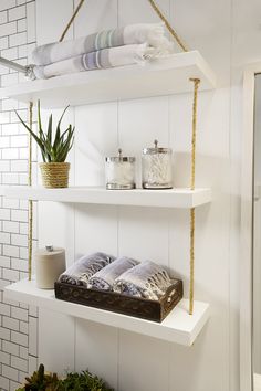 two white shelves with towels and plants on them are hanging from the ceiling in a bathroom