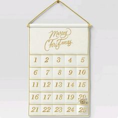 a white and gold christmas calendar hanging on a wall with the words merry christmas written across it