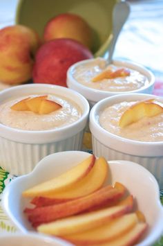 four small white bowls filled with oatmeal and peaches next to apples