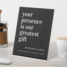 a sign that says, your presence is our greatest gift next to a cup of coffee