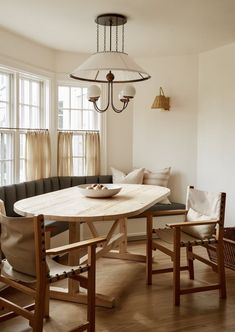 a dining room table with two chairs and a bench in front of it, next to a window