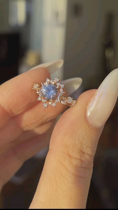 a woman's hand holding an engagement ring with blue and white stones on it