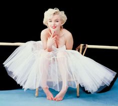 a woman sitting on top of a chair wearing a white dress and holding a wooden stick