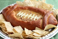 a football shaped hot dog on a plate with chips