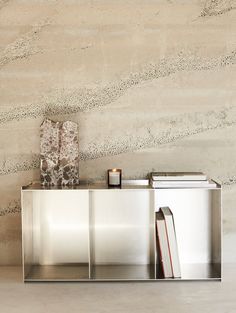 a book shelf with two books on it in front of a wall that is made out of concrete