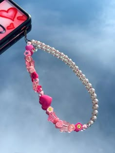 a cell phone hanging from the side of a car with beads and hearts attached to it