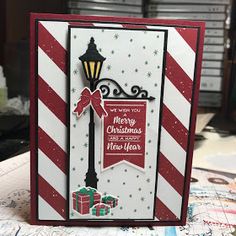 a handmade christmas card with a street light and presents on the table next to it