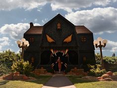 a large house with an evil face on it's front door and two giant pumpkins in the yard