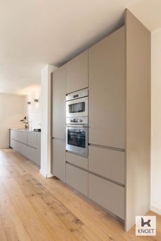 an empty kitchen with stainless steel appliances and wood flooring