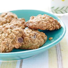 three oatmeal cookies on a blue plate next to a glass of milk