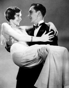 a man in a tuxedo is holding a woman's back and smiling