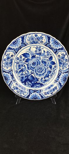 a blue and white plate sitting on top of a black table next to a black background