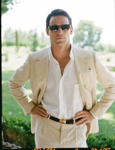 a man in a suit and sunglasses is posing for a photo with his hands on his hips