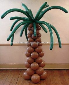 a palm tree made out of balloons in the shape of brown balls on a wooden floor