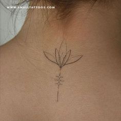 the back of a woman's neck with a small flower tattoo on her left side