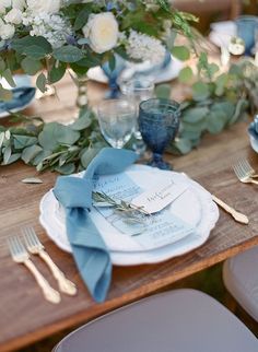 a wooden table topped with plates and silverware next to flowers on top of it