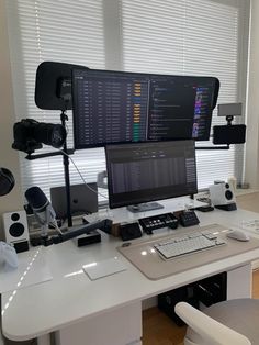 a desk with a computer monitor and keyboard on top of it next to two speakers