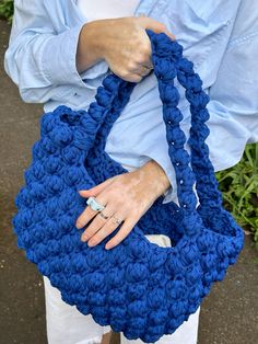 a woman holding a blue crocheted purse