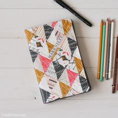 an open notebook sitting on top of a white table next to colored pencils and markers