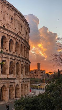 the roman colossion at sunset with people walking around and looking up into the sky