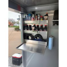 the inside of a trailer with bottles and other items on it's shelfs