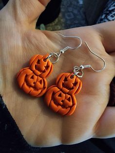 a pair of earrings with carved pumpkins on them are being held in someone's hand