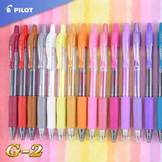 many different colored pens lined up in a row on a pink and yellow striped background