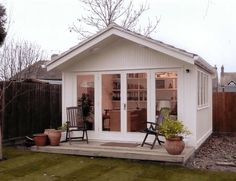 a small white shed sitting on top of a grass covered yard