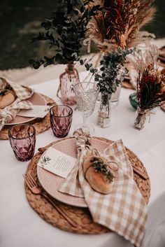 the table is set with plates, napkins and vases on top of it