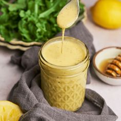 a spoon is pouring dressing into a jar