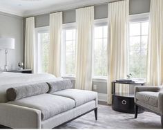 an image of a bedroom setting with white furniture and beige drapes on the windows