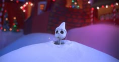 a small figurine sitting on top of a pile of snow in front of christmas lights