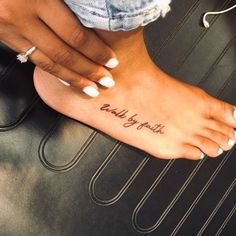 a woman's foot with a tattoo that reads, walk by faith