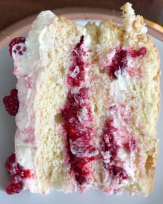 a piece of cake with white frosting and raspberry toppings on a plate