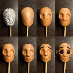 six different types of masks on sticks with faces and noses painted on them, all lined up in the same row