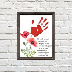 a red handprint on a white brick wall next to a framed print with an image of two poppies