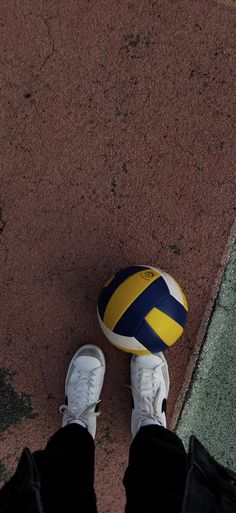 a person standing next to a yellow and blue ball on the ground with their feet up