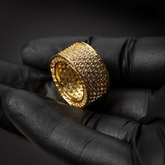 a gold ring is shown in the palm of someone's hand with black gloves