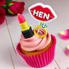 a cupcake with pink frosting and a ring on top that has a sign saying hen next to it